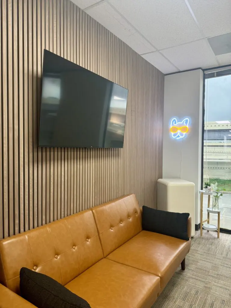 50" TV mounted on walnut acoustic paneling in an office, demonstrating our commercial TV mounting services in Houston.