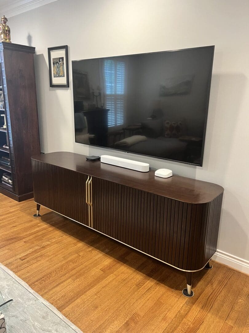 Professionally mounted TV above a stylish wooden entertainment center, highlighting the H-Town Handyman’s expert TV mounting and home organization services.