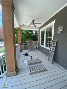 A porch with a black cat laying on the ground.