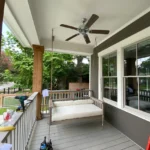 A porch swing with a ceiling fan on it.