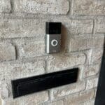A wall mounted video doorbell with brick background