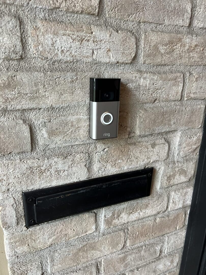 A wall mounted video doorbell with brick background