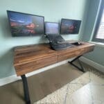 A desk with two monitors and a laptop on it.