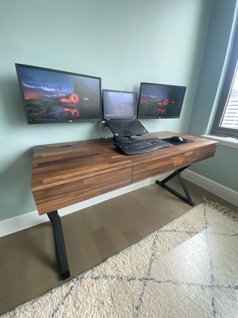 A desk with two monitors and a laptop on it.