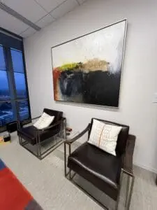 Office with two chairs and a painting mounted, creating a welcoming atmosphere.