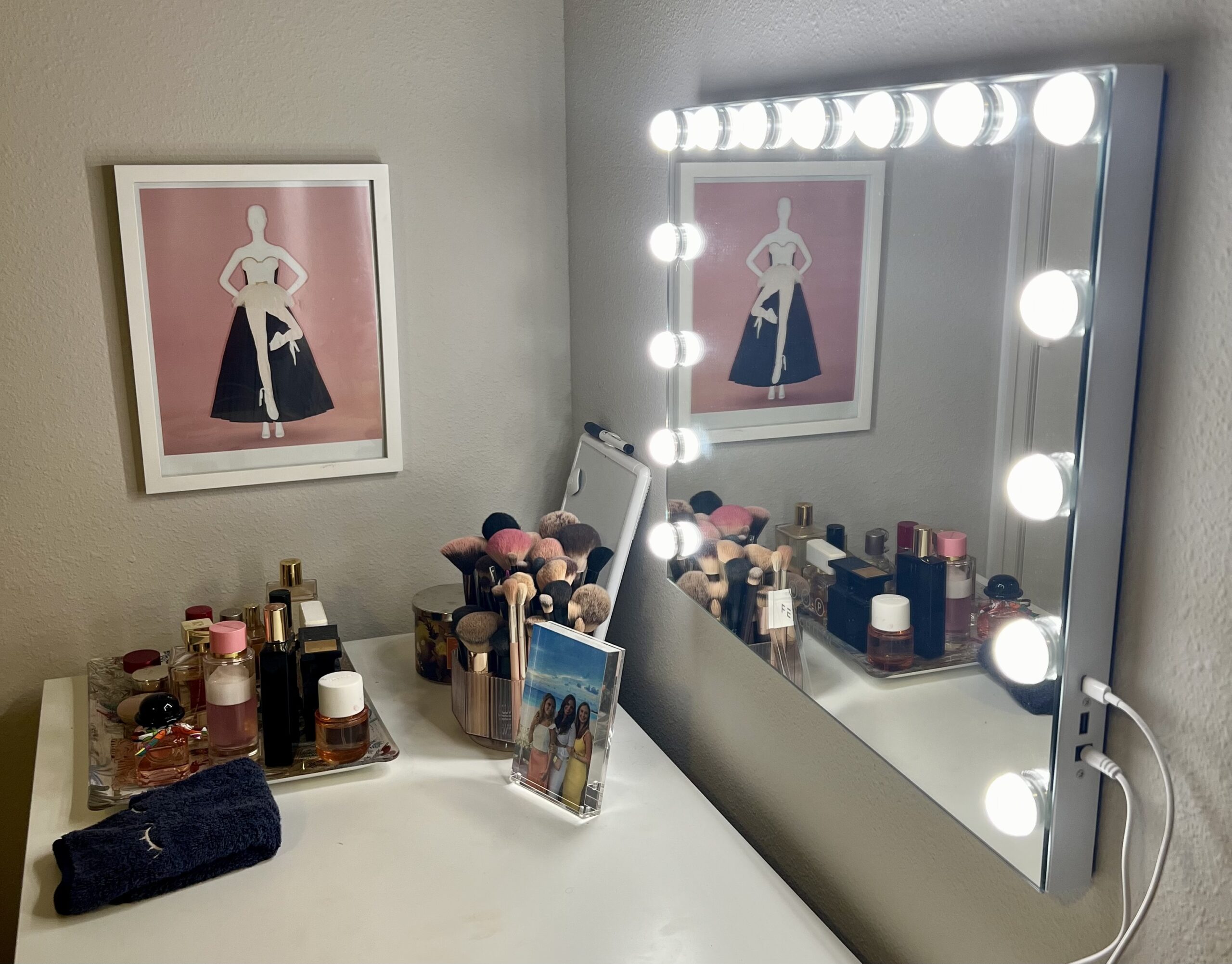 Vanity mirror with lights, makeup brushes, and perfume bottles.