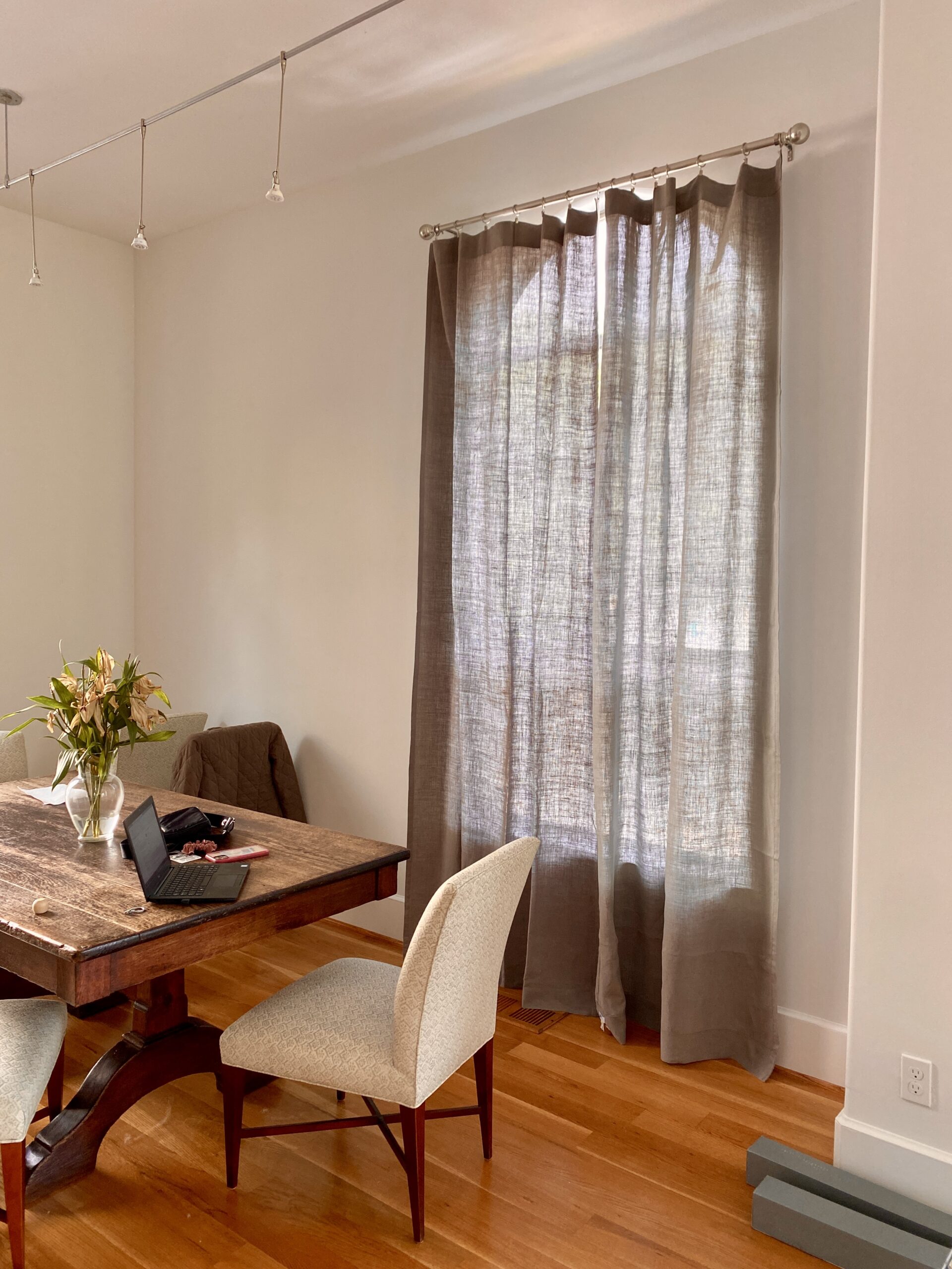 Grey linen curtains installed in a dining room, adding a touch of sophistication to the space.