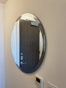 A round convex mirror is installed to add depth and enhance any room's decor.