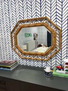 Stylish bedroom with a hexagonal rattan mirror, reflecting custom mirror installation for family-friendly spaces.