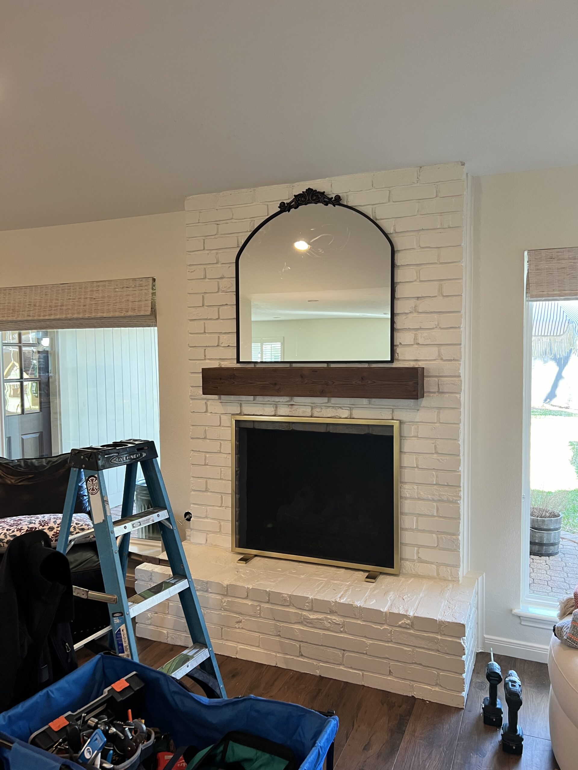 White brick fireplace complemented by an arched mirror, creating a cozy, stylish living space.